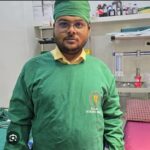 रुग्णालयातील ऑपरेशन थिएटरमध्ये हिरव्या शस्त्रक्रिया पोशाखात उभा असलेला डॉक्टर